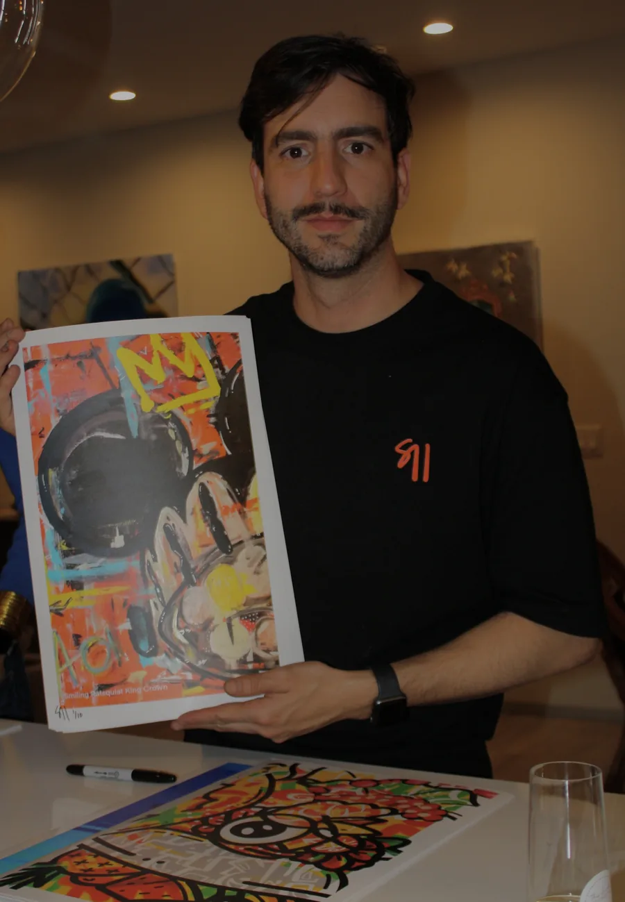 Juan Salazar with a signed print of Smiling Ratsquiat, King Crown